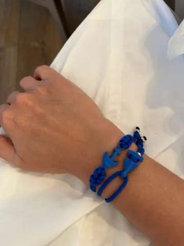 Muñeca con una pulsera de cuerda azul con un ancla y un nudo trenzado sobre una camisa blanca