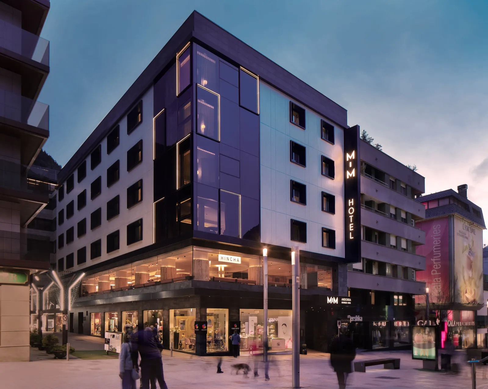 Fachada del hotel MiM Andorra al atardecer, un edificio moderno de color oscuro en una calle peatonal de Andorra la Vella