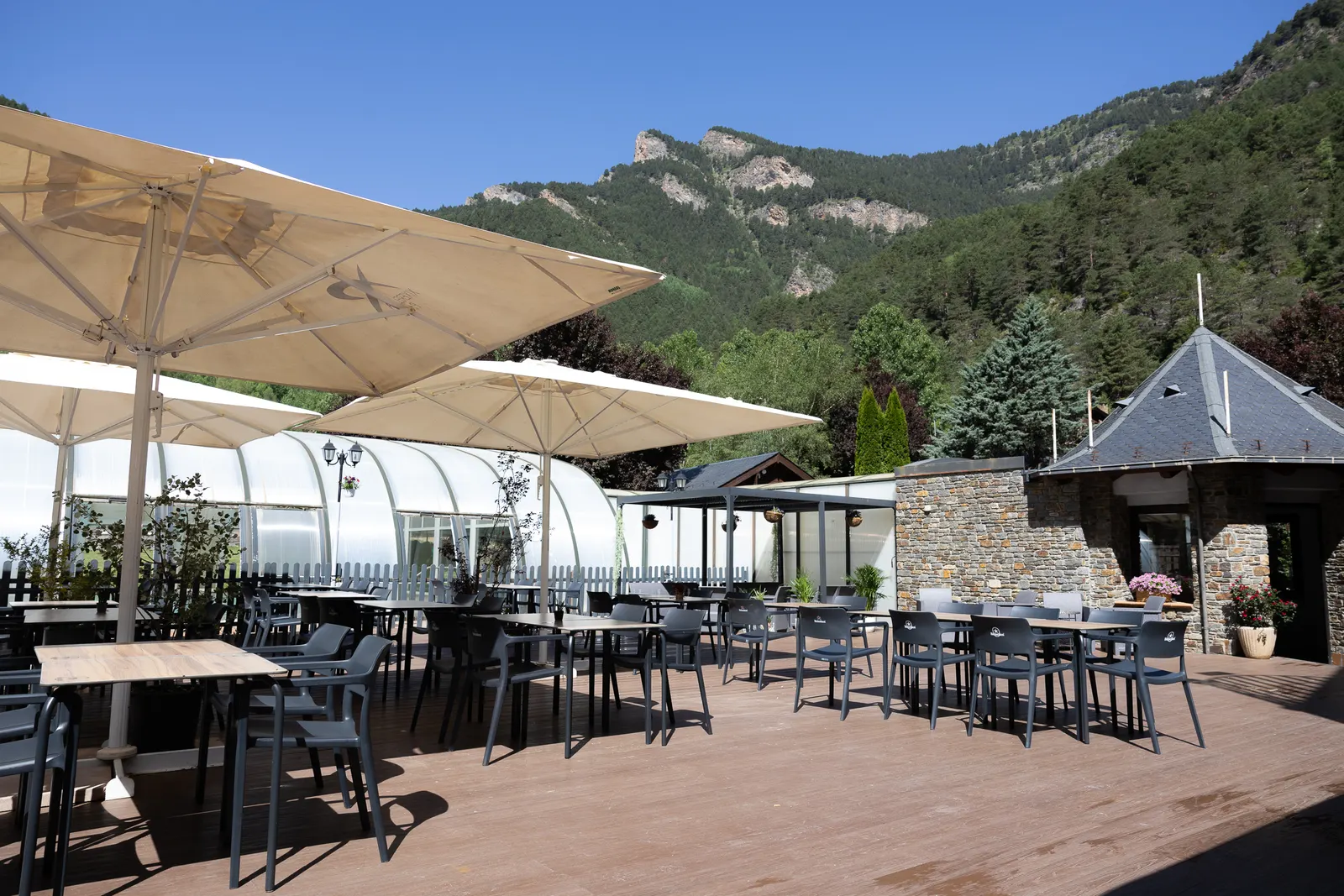 Terraza de L'Oasi en el Restaurant Andrea, con sombrillas blancas, mesas y las montañas de La Massana detrás