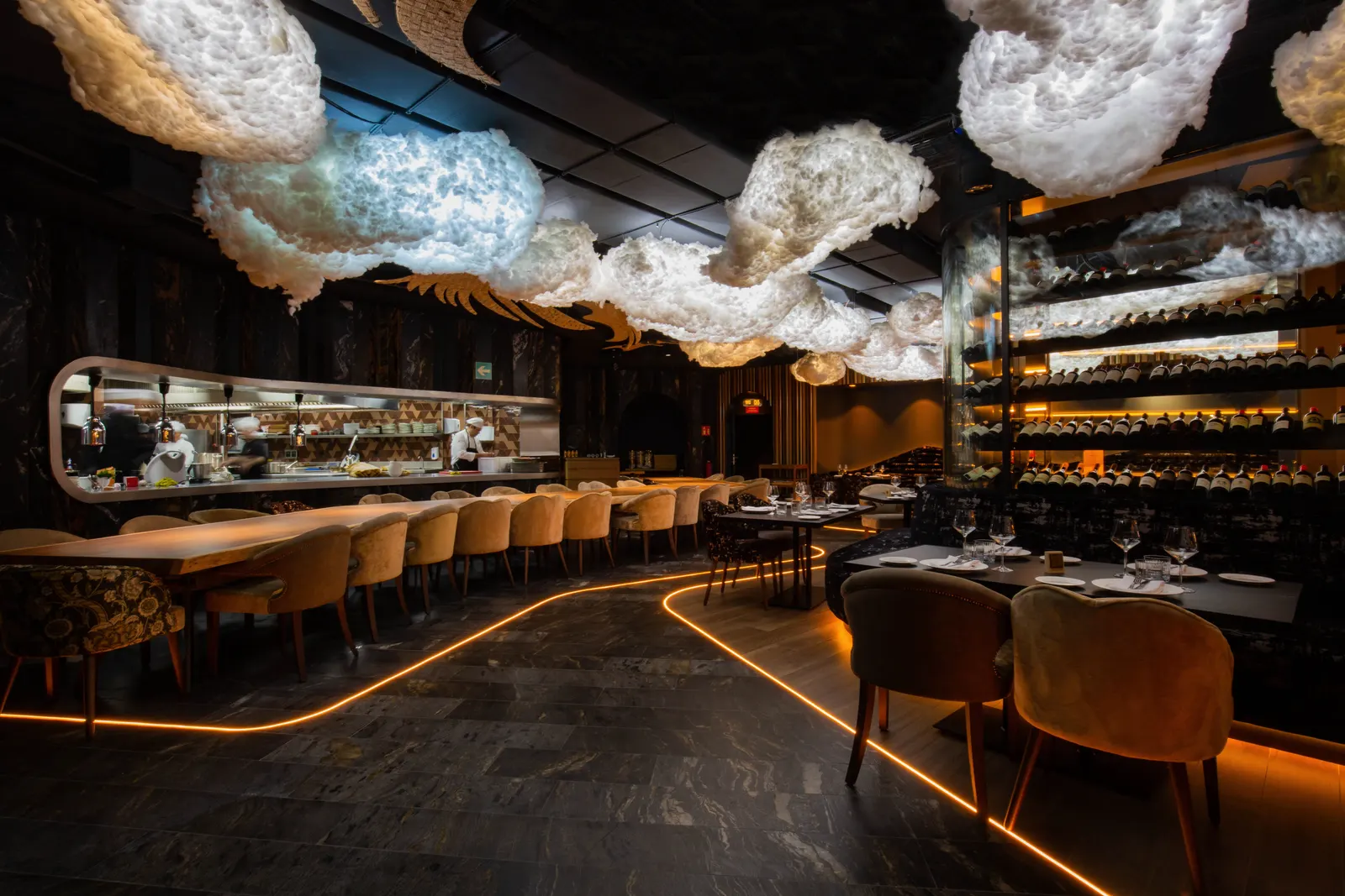 El Restaurante de UNNIC, con una barra larga iluminada en naranja y nubes blancas colgando del techo
