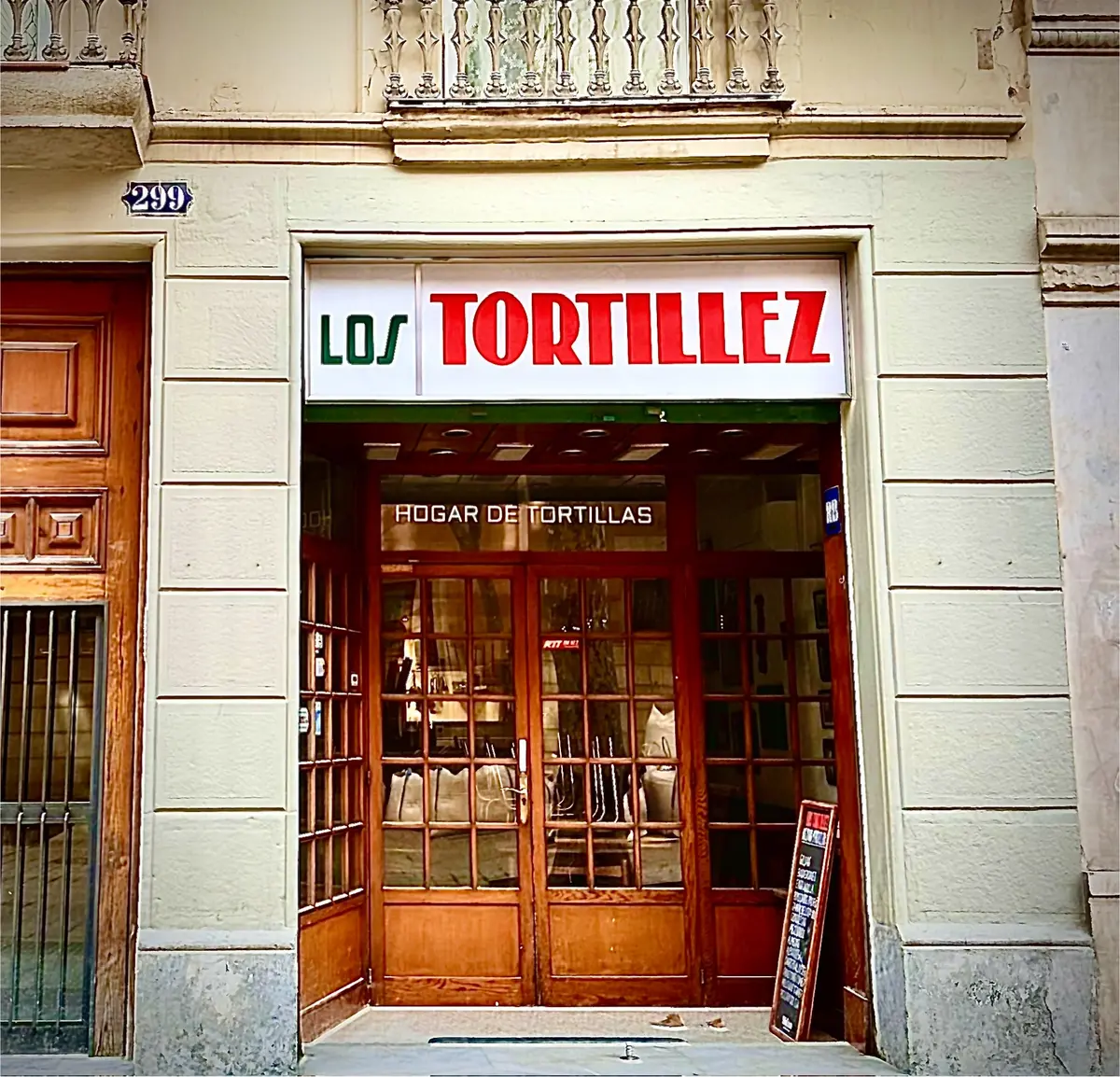 Fachada de Los Tortillez en Consell de Cent, con el letrero rojo y verde y el rótulo Hogar de tortillas sobre la puerta de madera