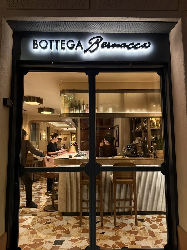 Fachada de Bottega Bernacca de noche, con la barra iluminada al fondo